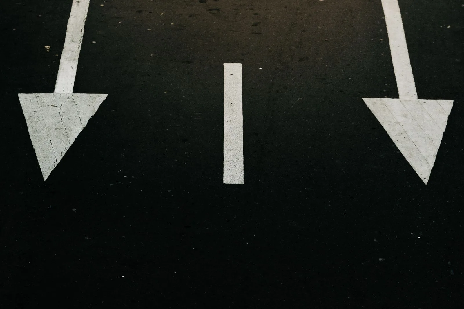 Traffic direction arrows painted on a city street, symbolizing a choice between paths