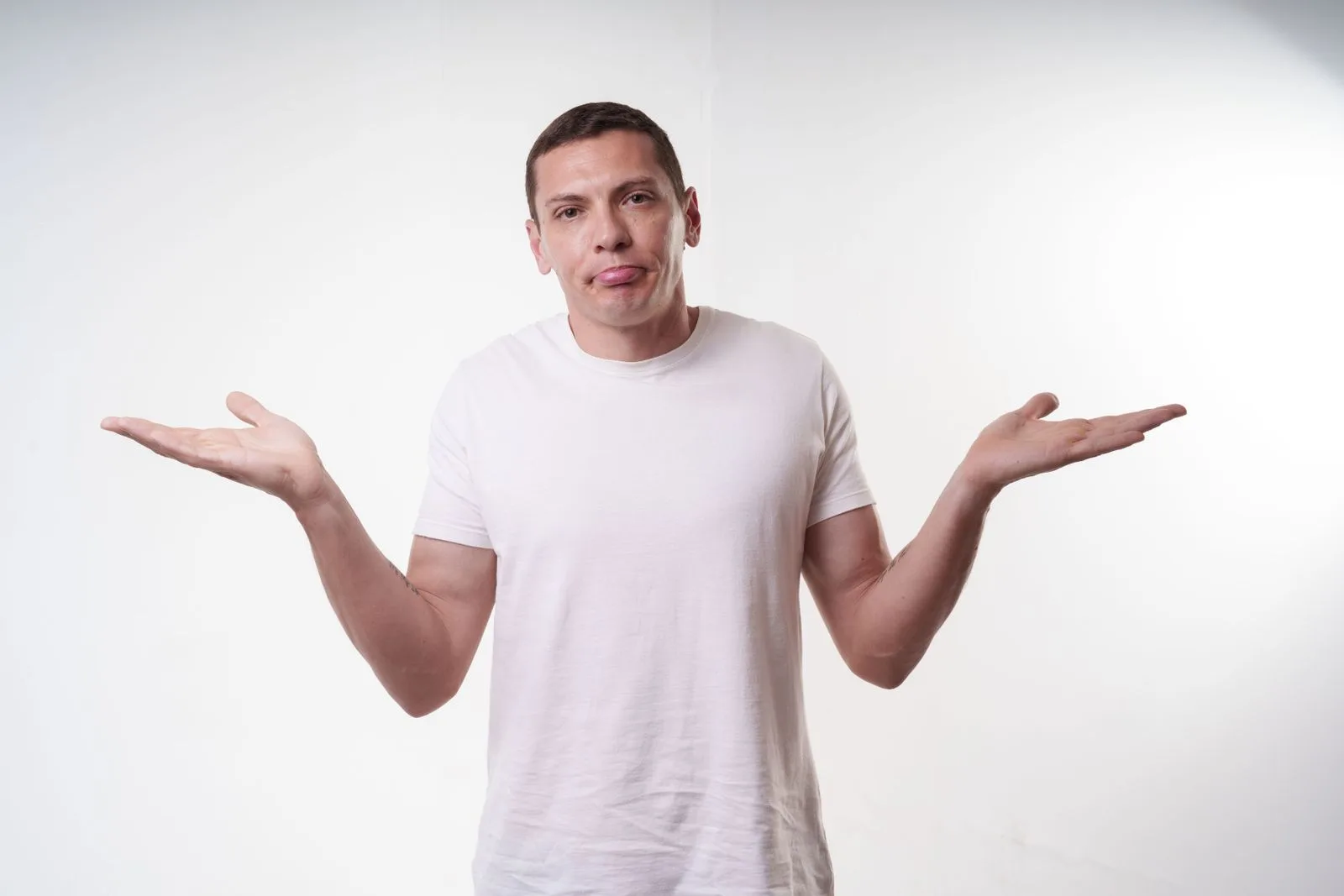 A man shrugging with a confused expression against a plain background