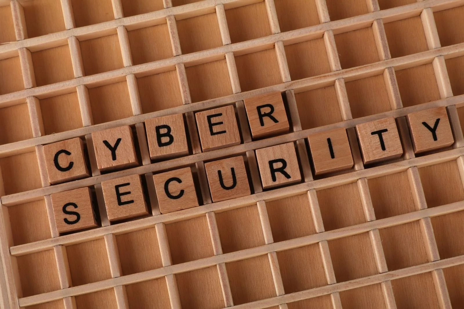 Wooden blocks spelling out cyber security on a wooden grid background