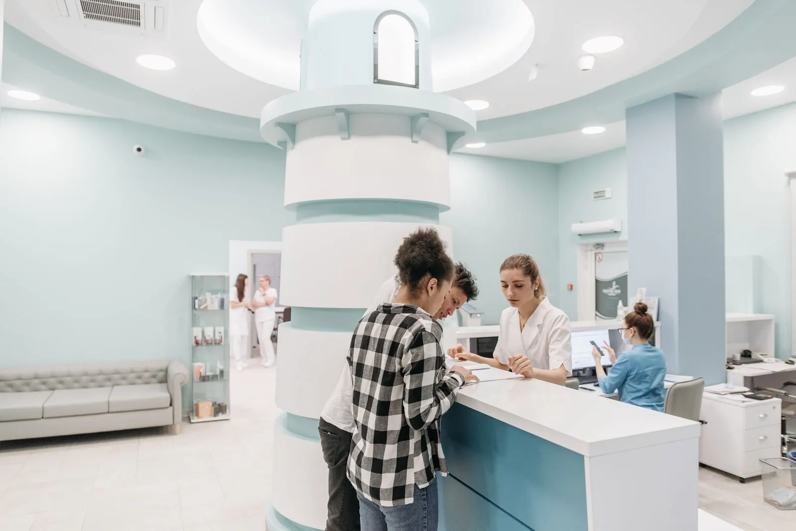 A patient at the reception desk of a bright medical clinic while staff attend the counter