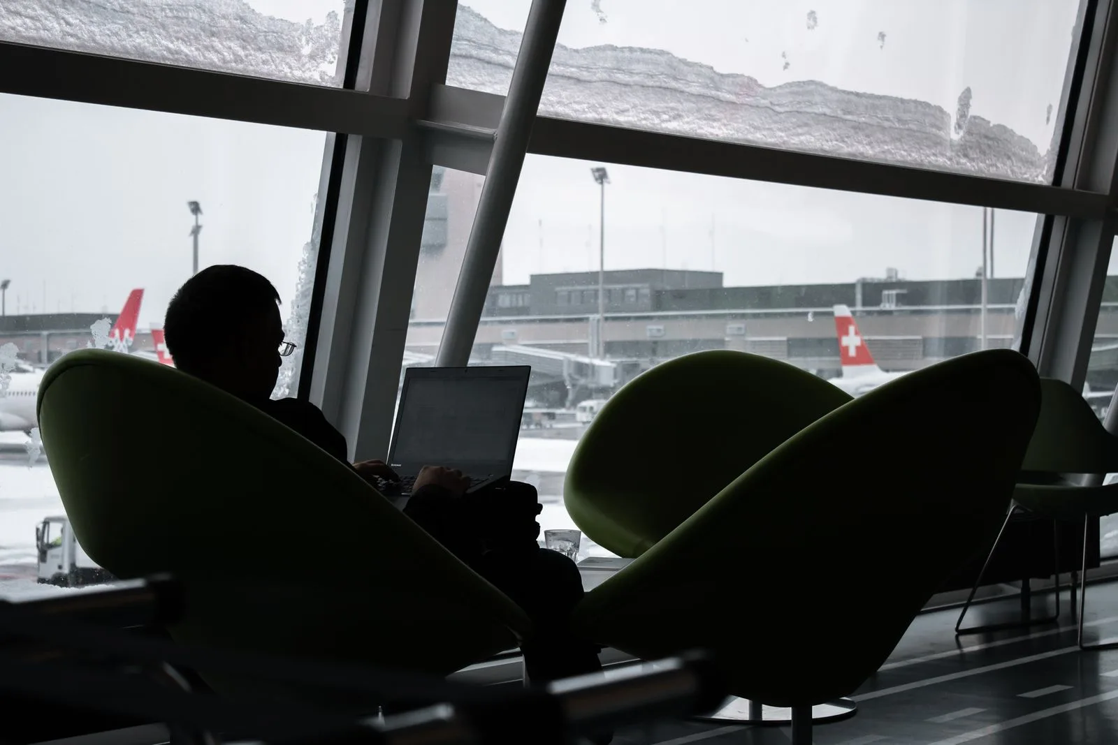 Silhouette of a person working alone on a laptop at an airport lounge