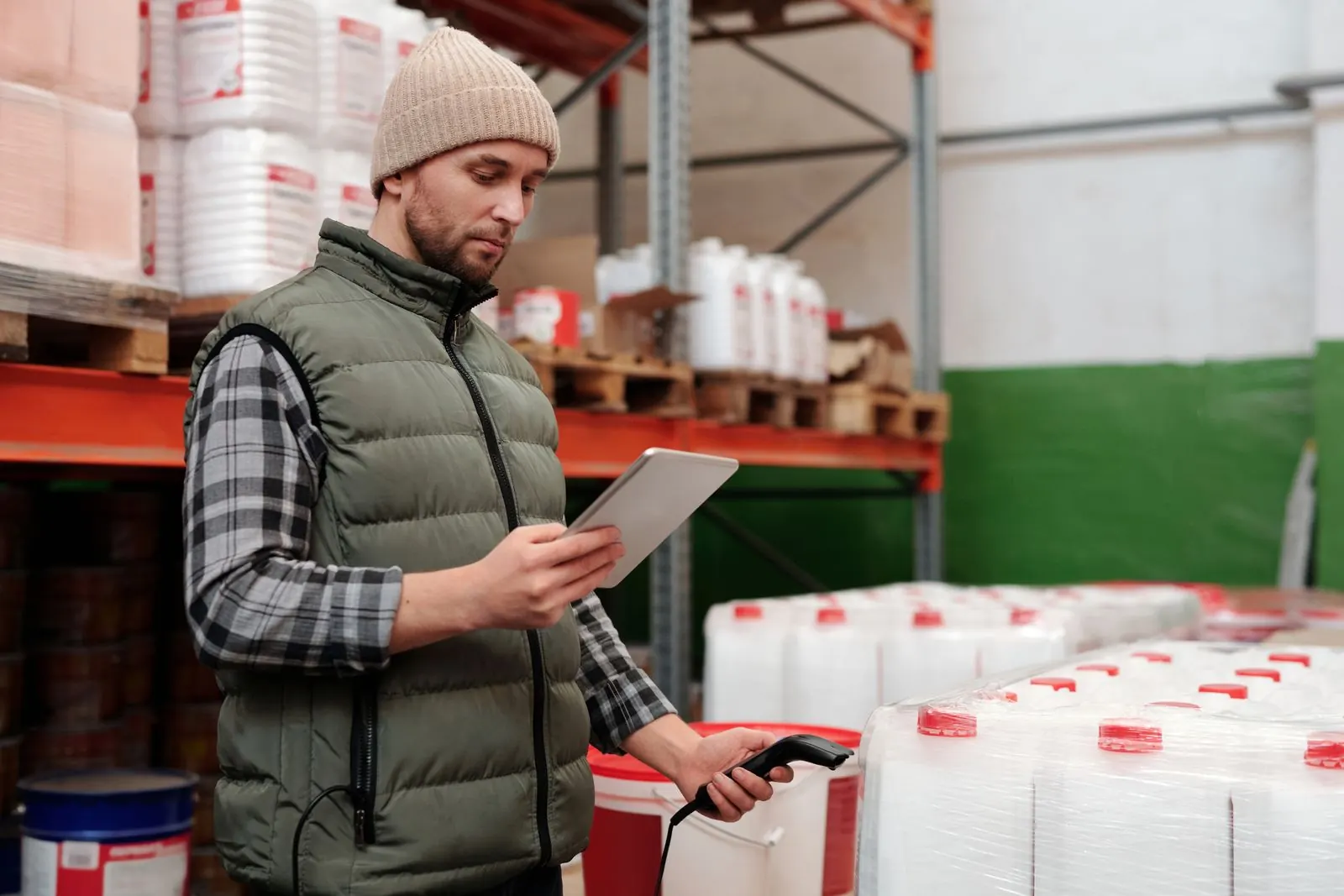 A warehouse worker checking stock on a tablet next to pallets of containers