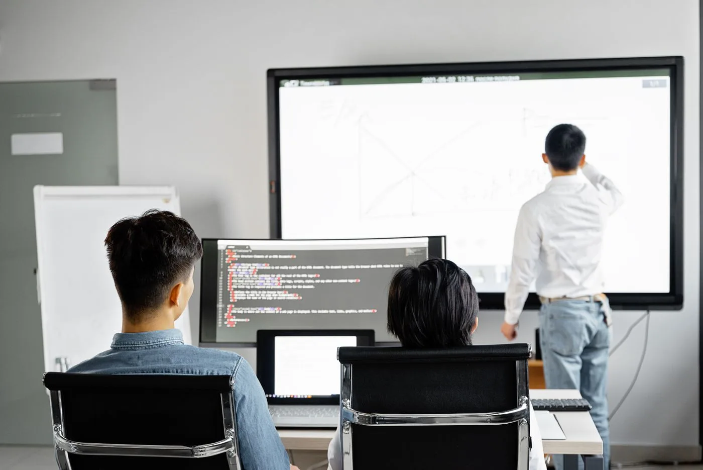 Two developers working at separate specialized workstations in a modern tech office