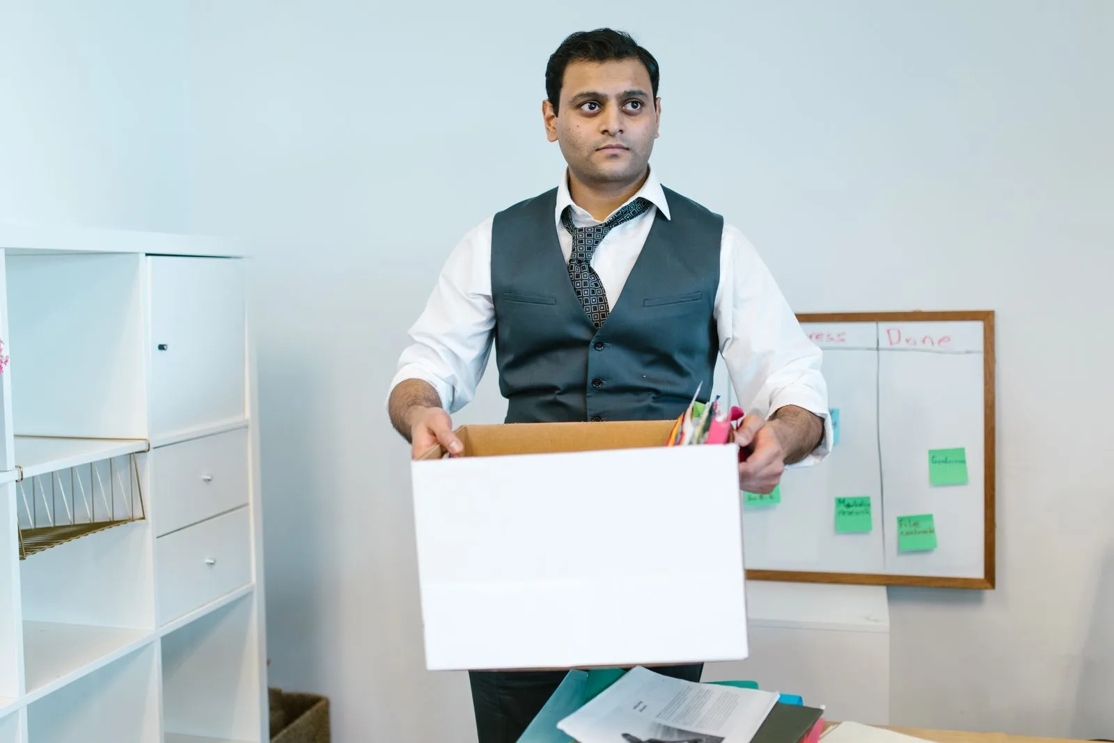 A professional packing personal belongings into a cardboard box at an office desk