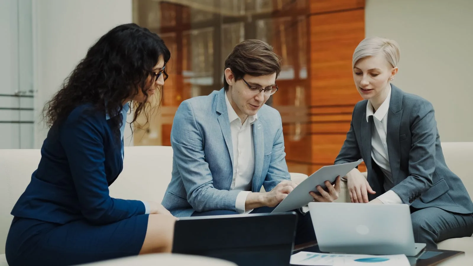 Three professionals collaborating around a table with digital devices, representing different hiring options