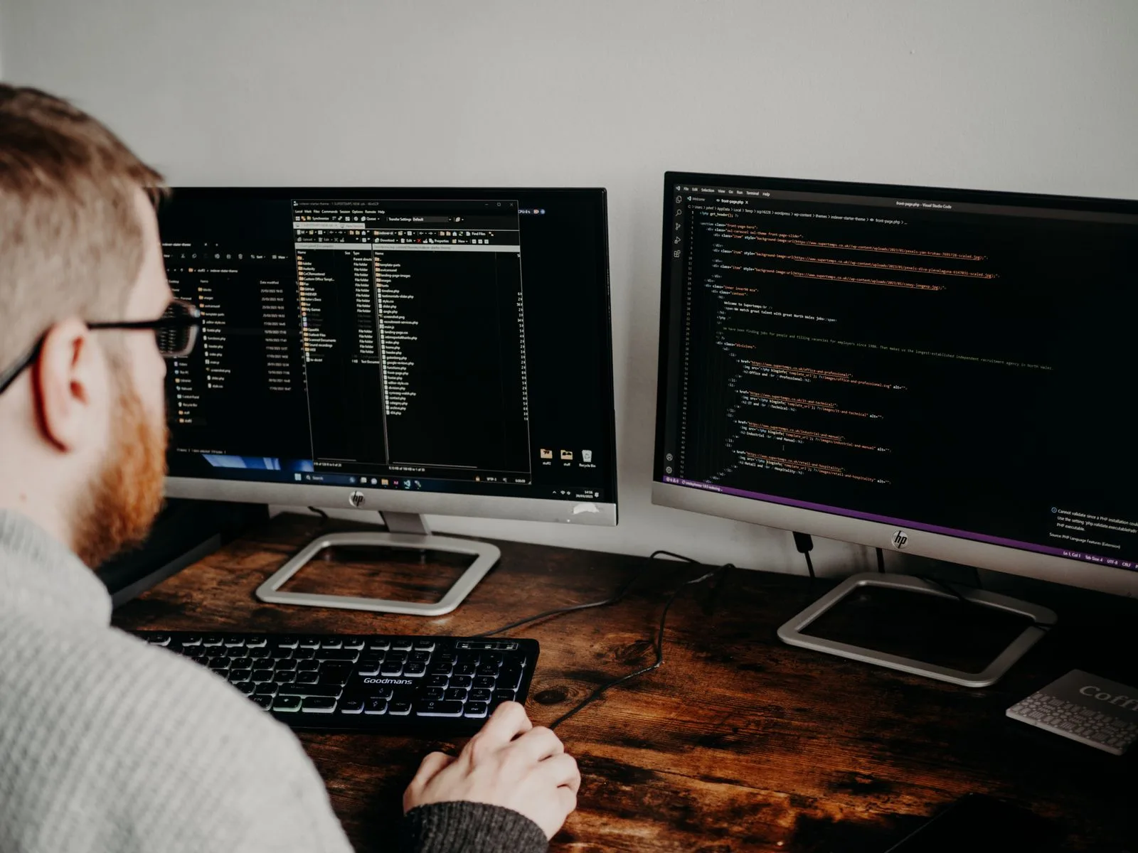 A software developer working on code across dual monitors in an office