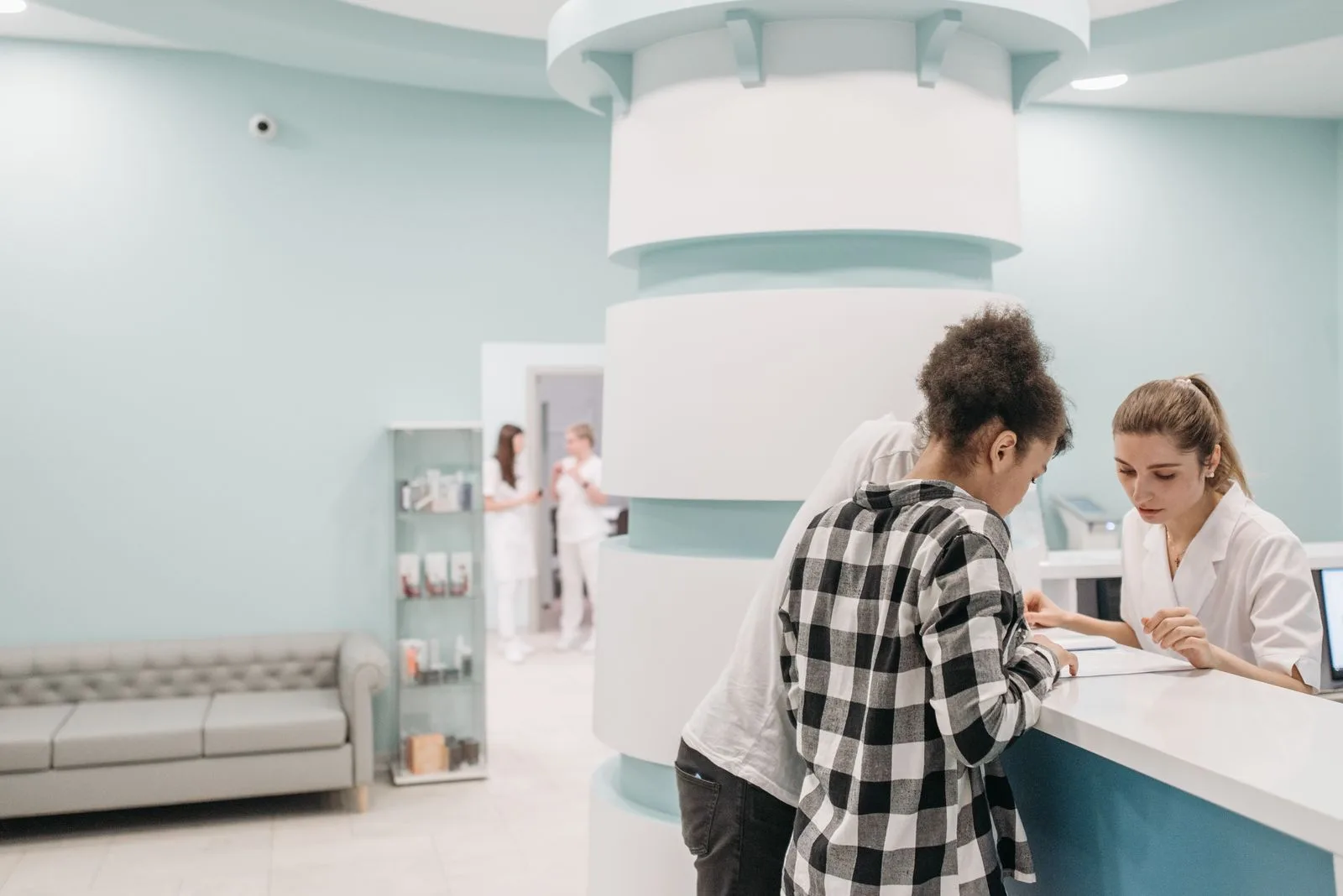 Healthcare staff assisting a patient at a modern clinic reception desk