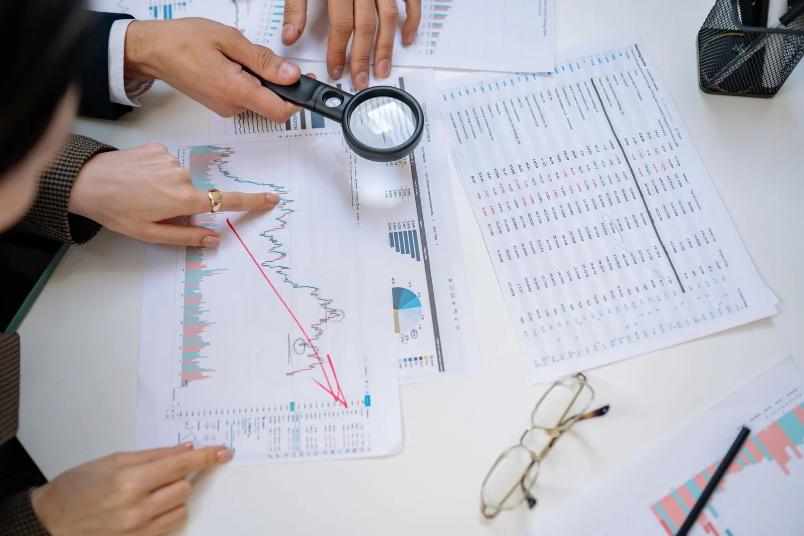 Business professionals examining documents together with a magnifying glass