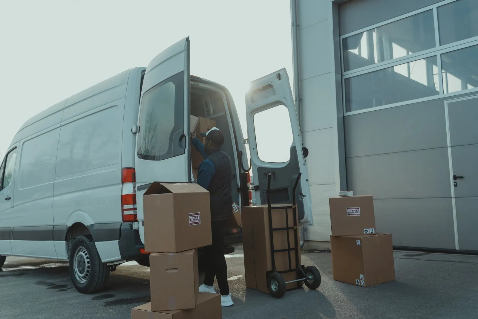 A delivery worker loading boxes into a van at a warehouse dock