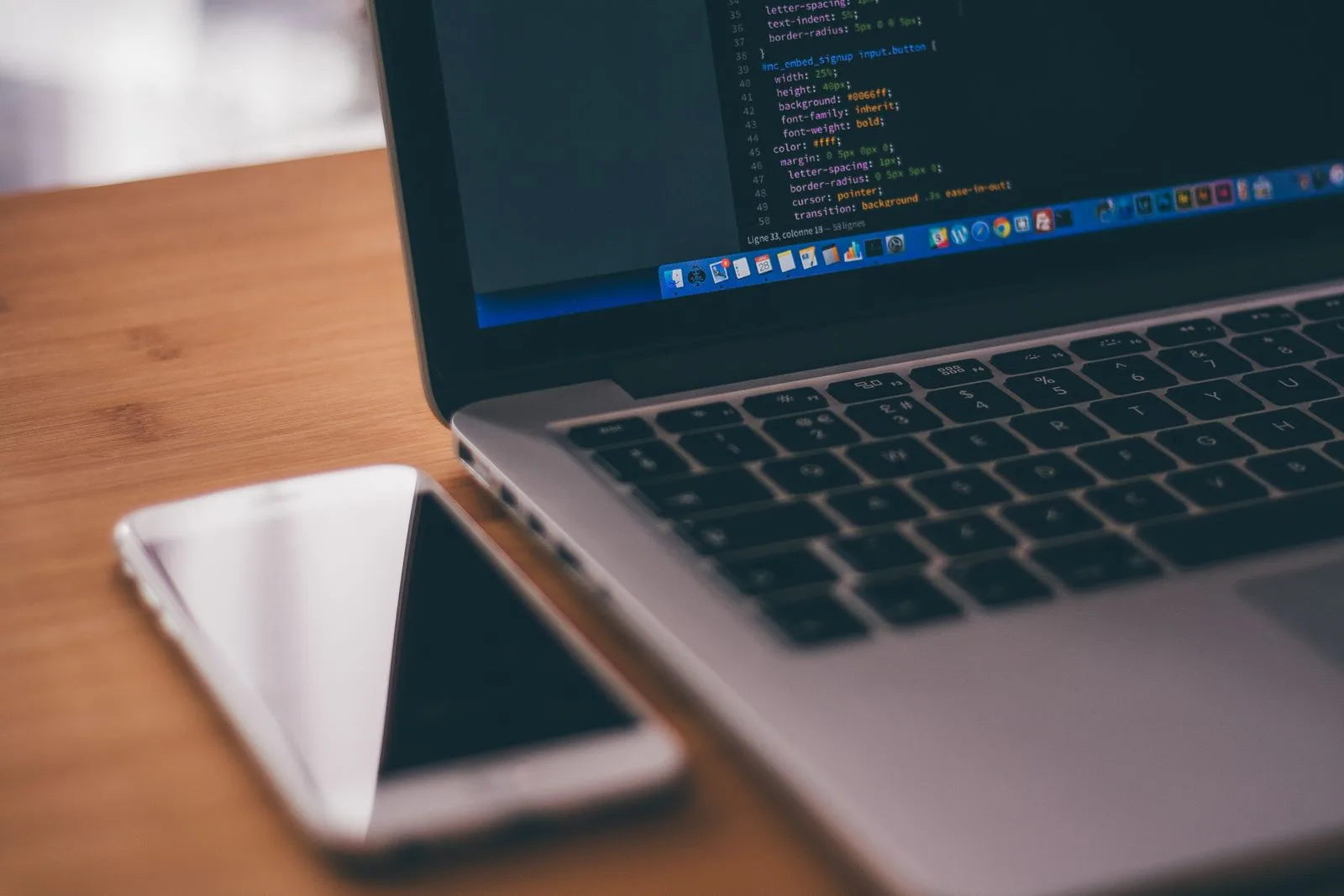 Laptop and smartphone side by side on a desk, representing the choice between native, web, and PWA app development
