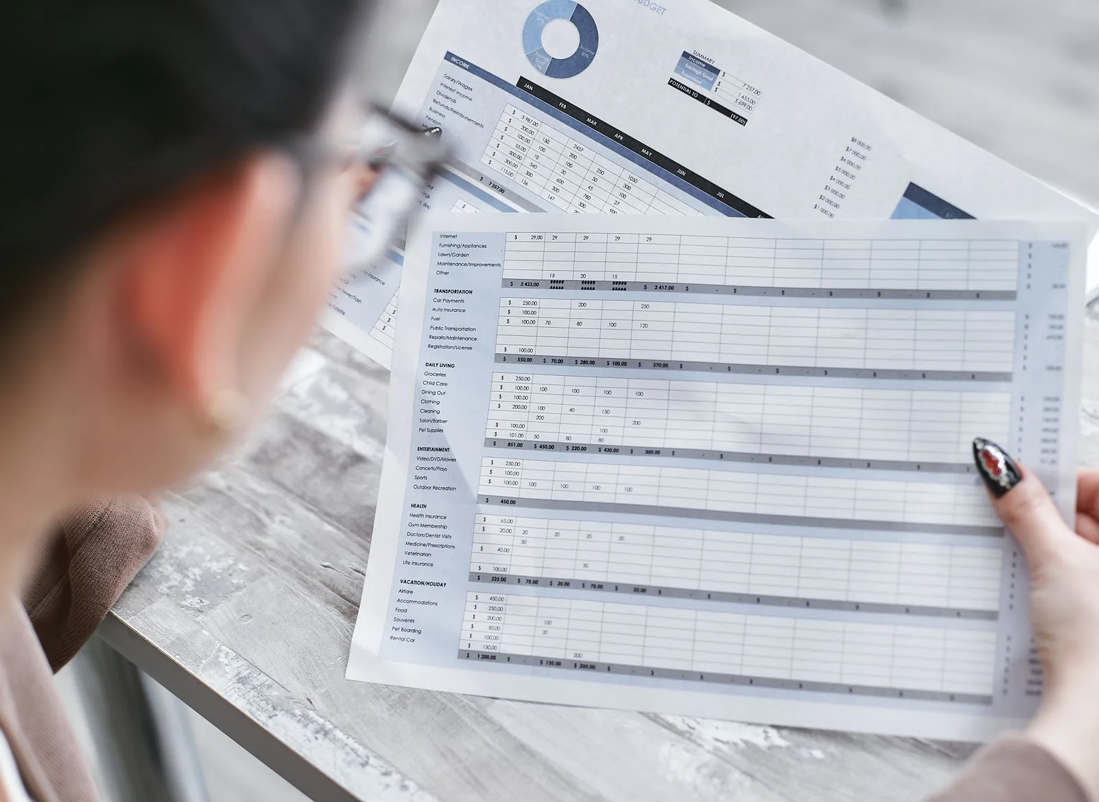 Businesswoman reviewing financial spreadsheets full of charts and numbers at her desk