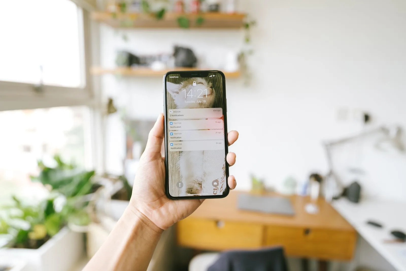 A hand holding a smartphone showing a notification, representing a proactive business alert