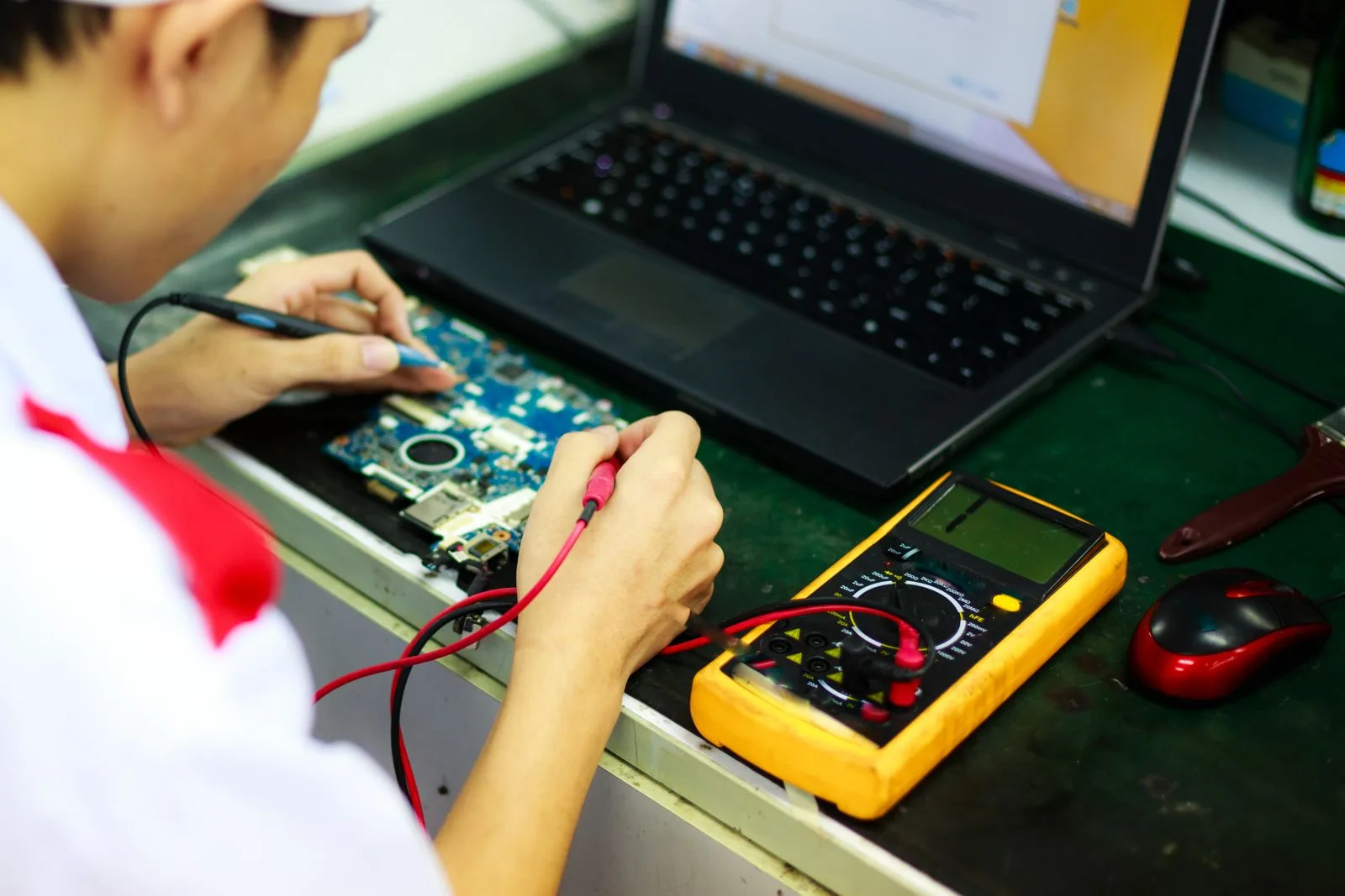 A technician working on a laptop using measurement tools, representing ongoing software maintenance