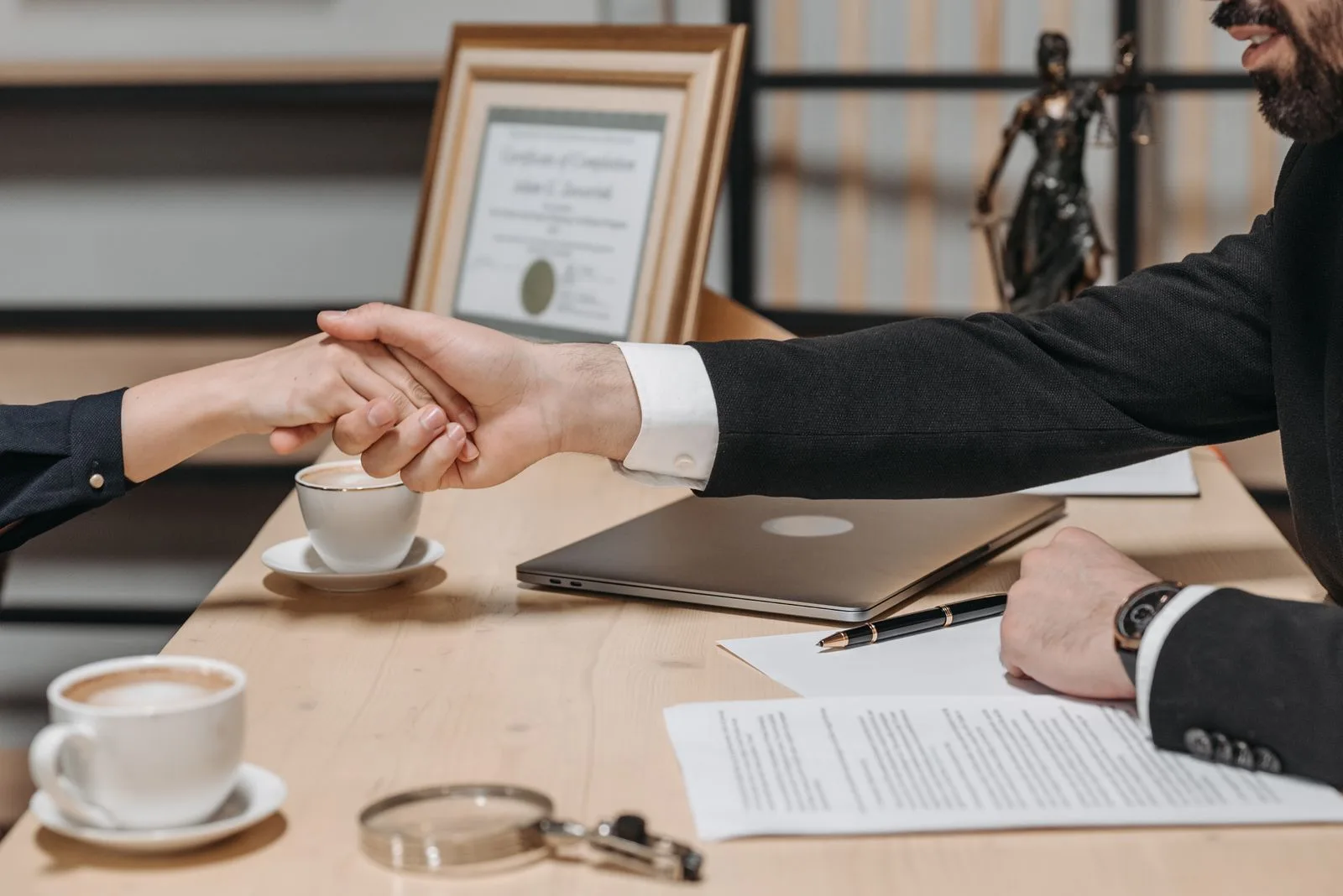 A formal handshake over a business contract on a desk