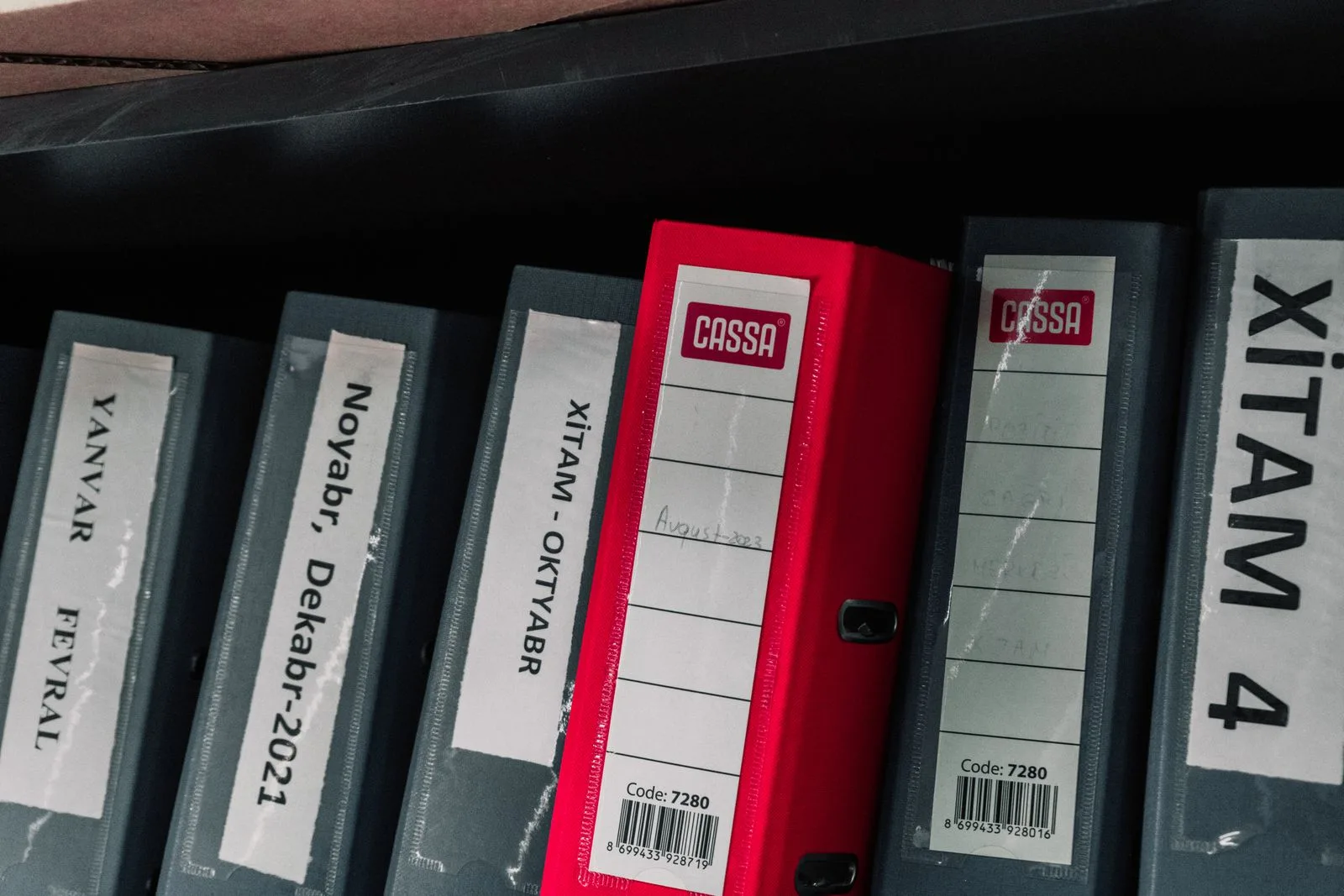 Color-coded office binders organized neatly in a storage shelf