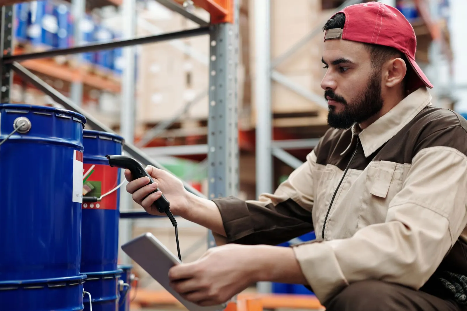 A warehouse worker scanning barrels with a handheld scanner and a tablet