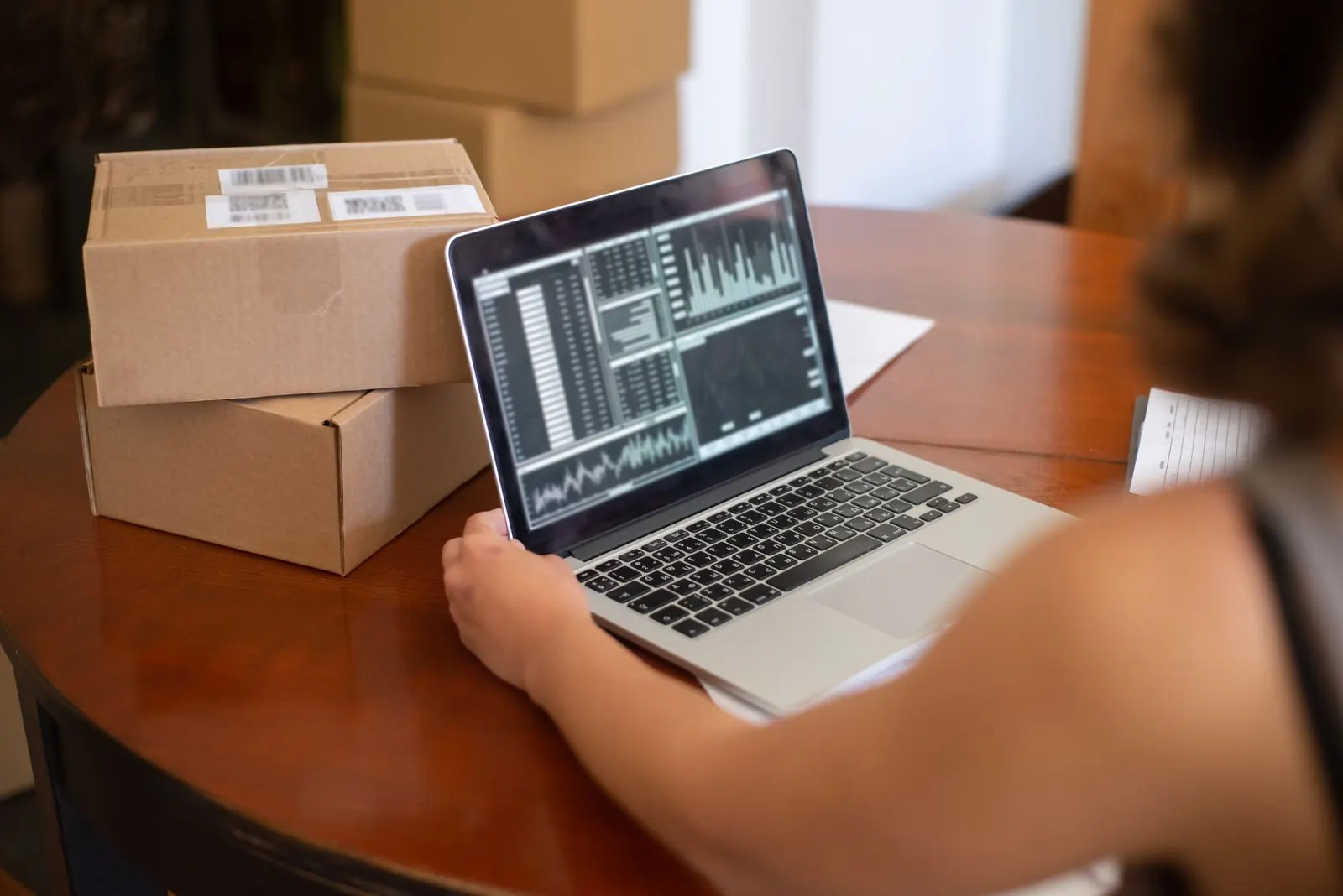 A small online seller at a table with a laptop and parcels