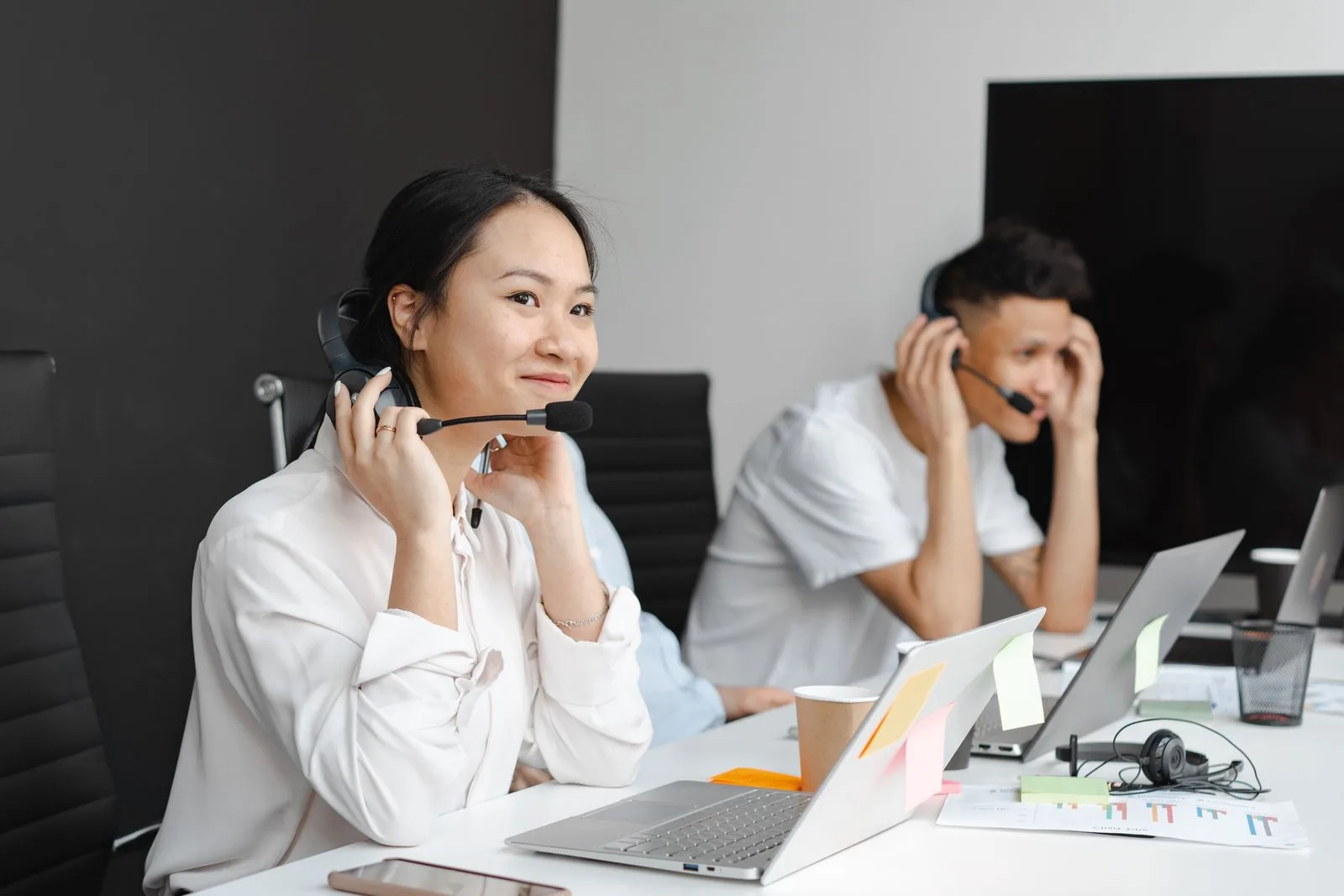 A diverse group of customer support agents working with laptops and headsets in a modern office