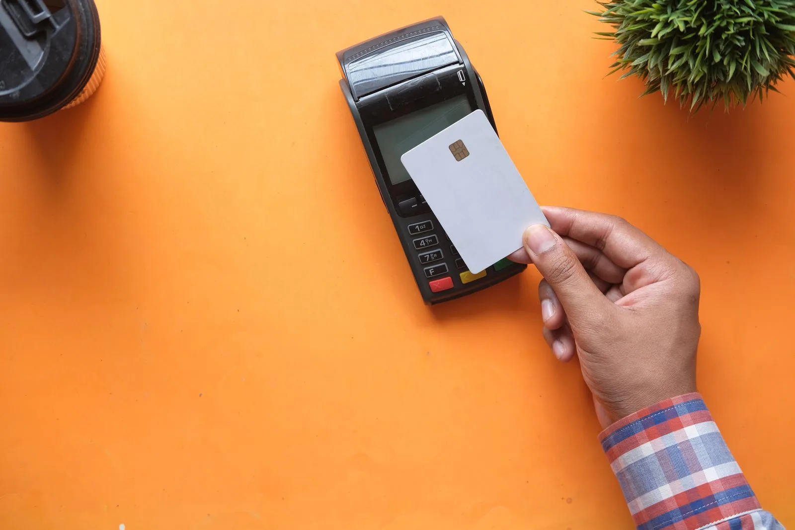 A person making a contactless payment with a credit card and card reader