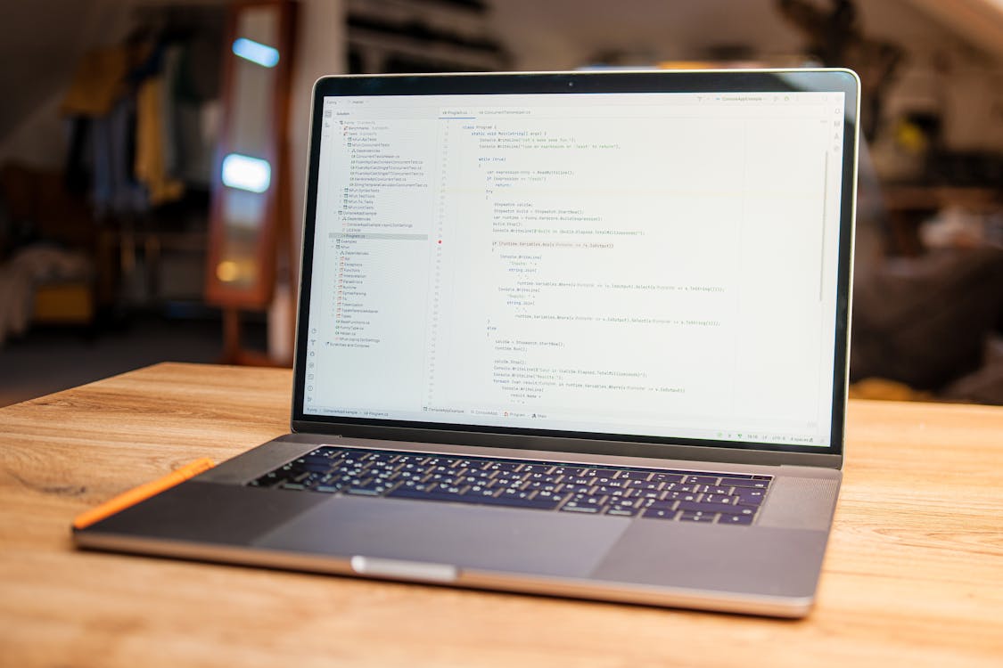 Open laptop with visible code on screen on a wooden desk in a modern workspace