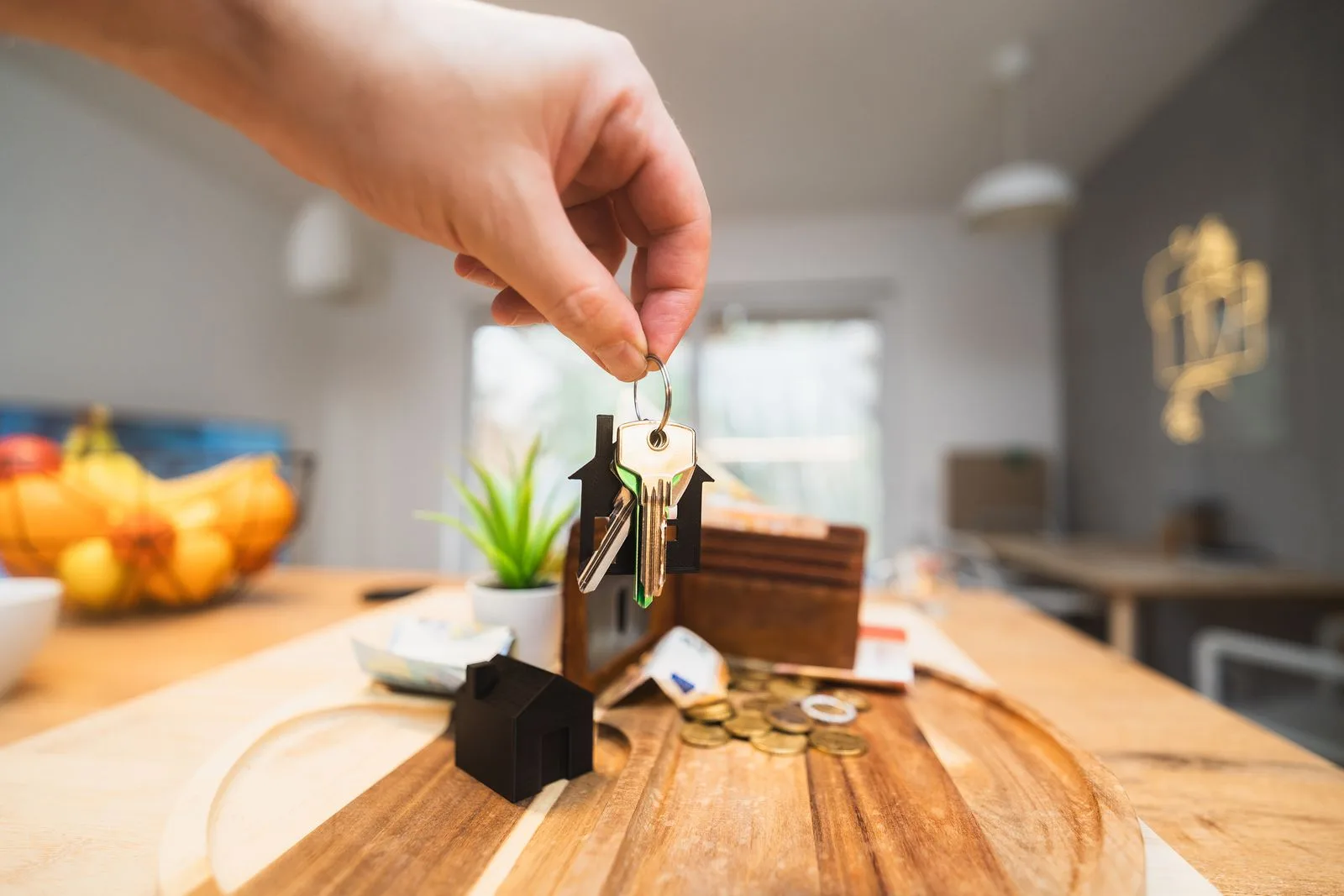 A hand holding house keys in a modern living room, representing rental property management