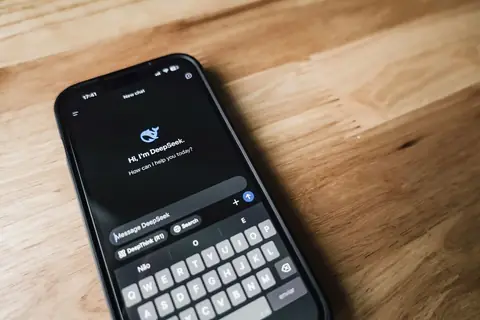 Close-up of a smartphone showing a chat app interface on a wooden table