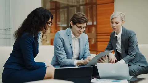 Three professionals collaborating around a table with digital devices, representing different hiring options
