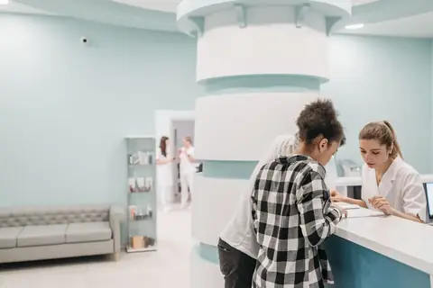 Healthcare staff assisting a patient at a modern clinic reception desk