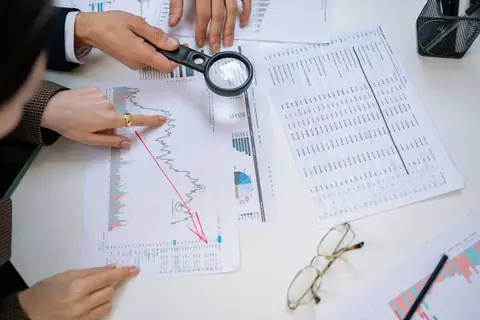 Business professionals examining documents together with a magnifying glass