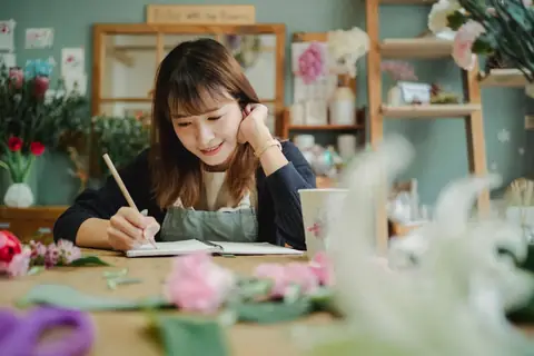 A small business owner in an apron writing notes by hand in her shop