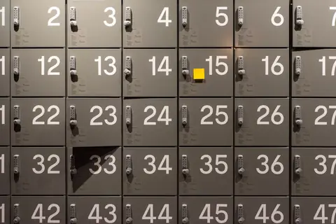 Rows of numbered electronic lockers with a single yellow sticky note attached to one