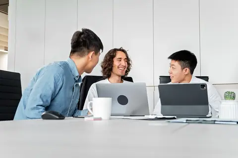 Diverse colleagues collaborating in a modern office with laptops and tablets — hybrid work in financial services