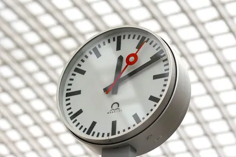 Close-up of a modern analog clock against a geometric background