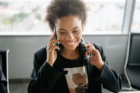 A cheerful call center agent talking on the phone while wearing a headset