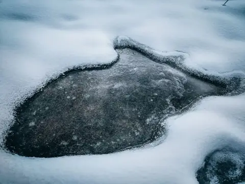 A frozen lake surface surrounded by snow