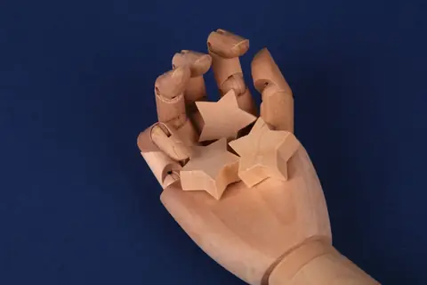 A wooden hand model holding star-shaped blocks, representing a customer rating