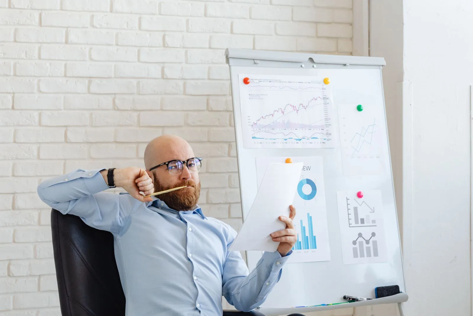 A businessman reviewing financial charts with a thoughtful, puzzled expression
