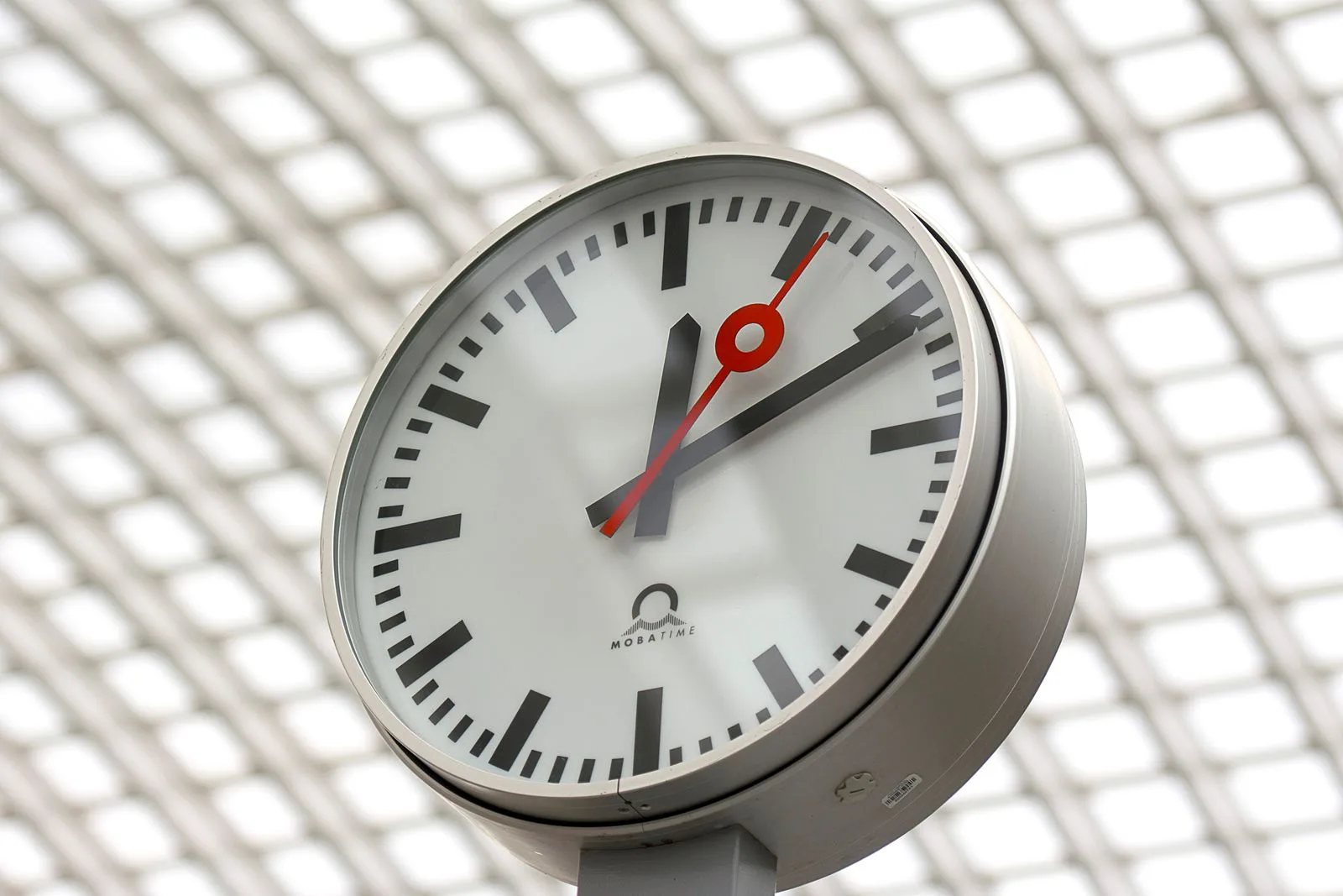 Close-up of a modern analog clock against a geometric background