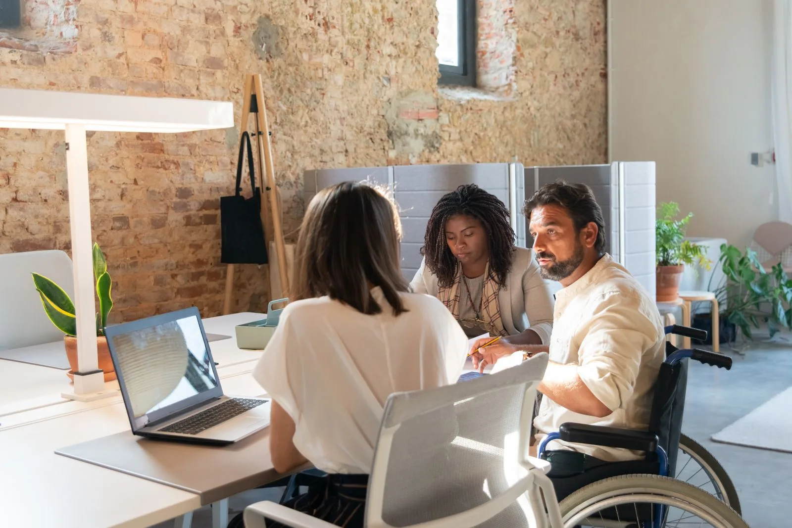 Team collaborating in a modern office, including a colleague using a wheelchair, representing inclusive and accessible web design