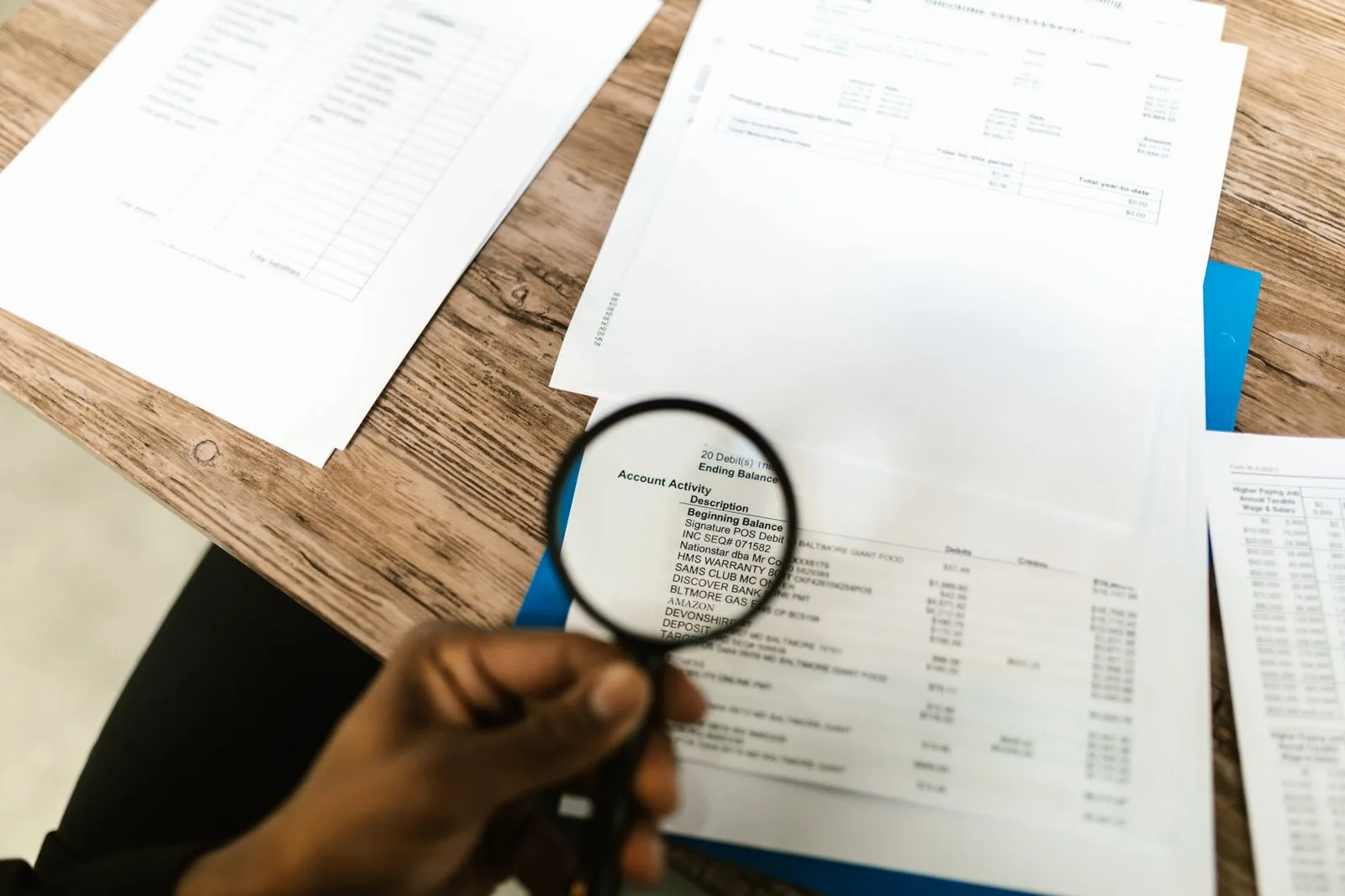 A hand using a magnifying glass to review documents closely