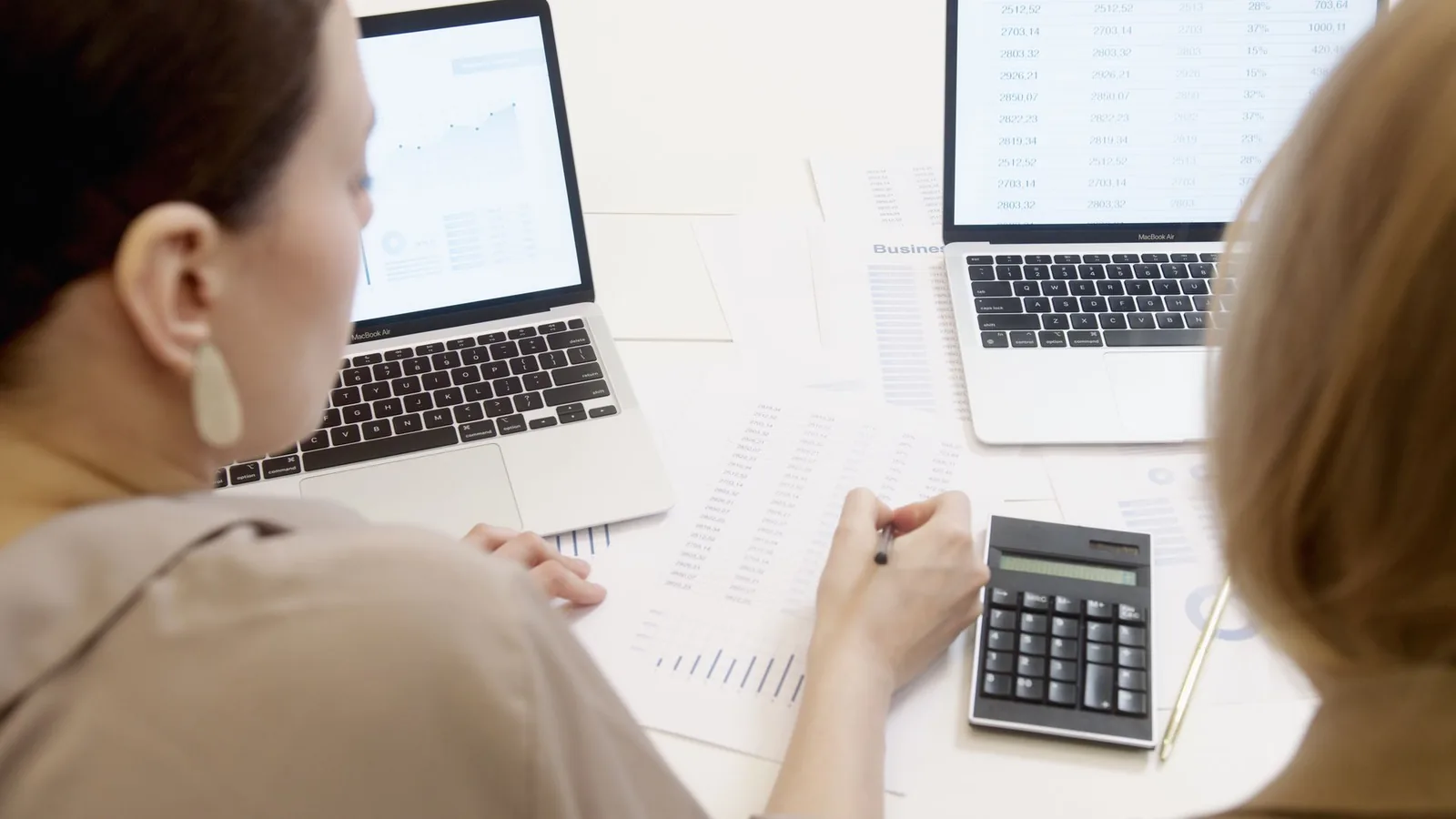 Office desk with a spreadsheet, calculator, and clock showing time spent on a manual weekly report