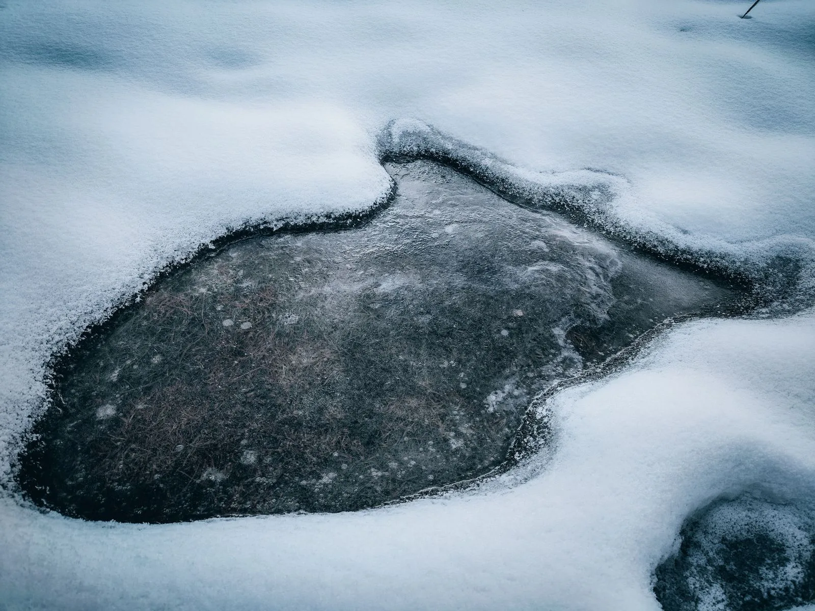 A frozen lake surface surrounded by snow