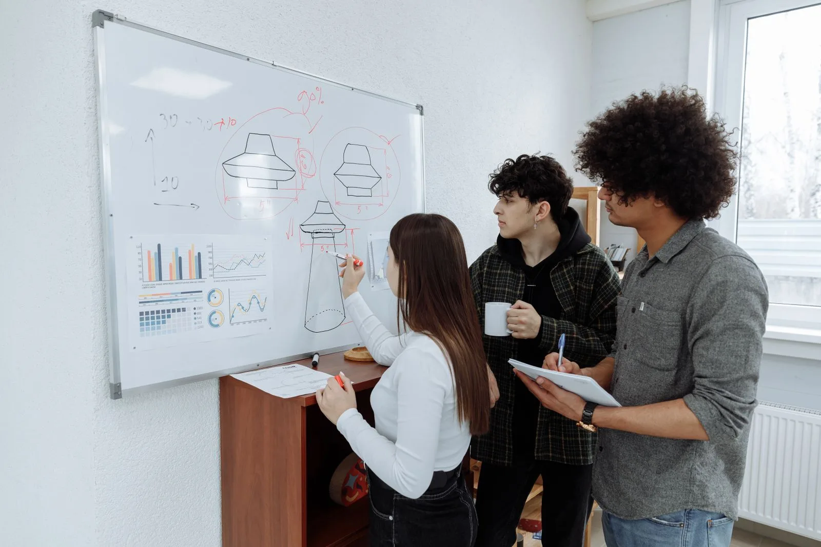 Young professionals brainstorming and sketching a product prototype on a whiteboard