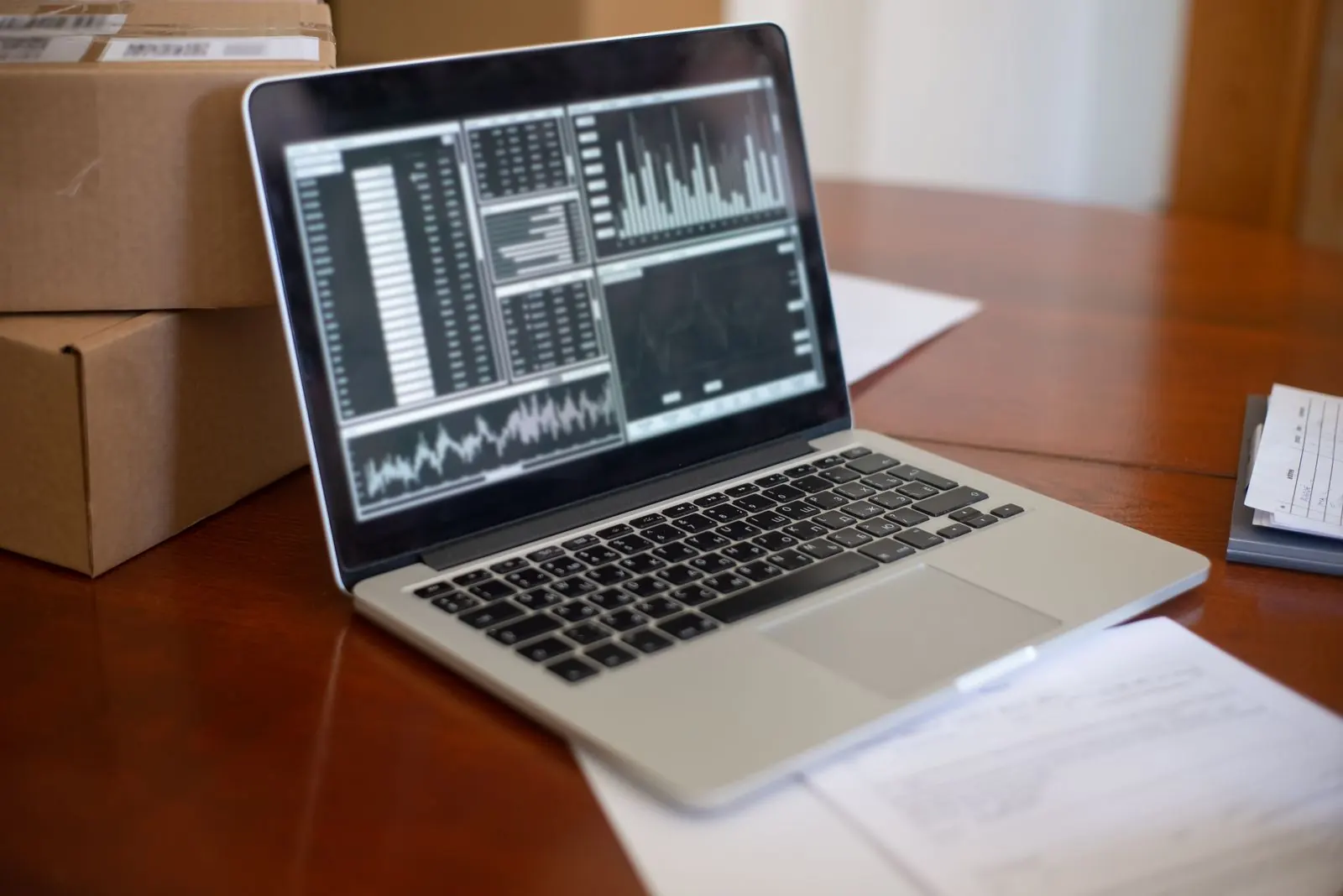 A laptop showing data tables and charts next to stacked cardboard boxes