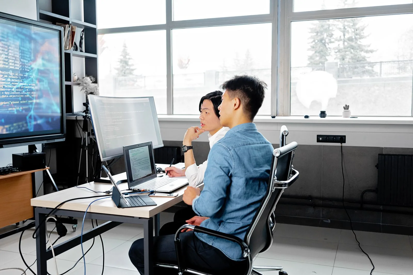 Two developers analyzing code together on computers in a modern office