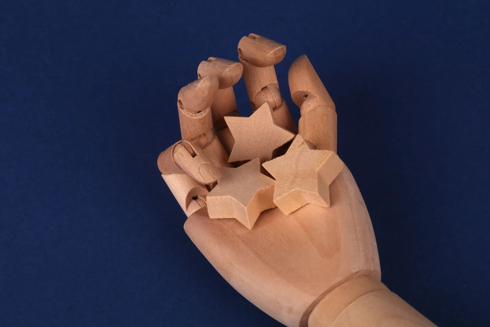 A wooden hand model holding star-shaped blocks, representing a customer rating